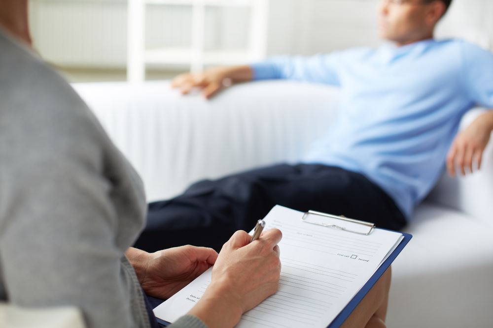 Female psychologist making notes during psychological therapy session